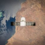 Satélite em órbita sobre a Terra, com o oceano visível ao fundo