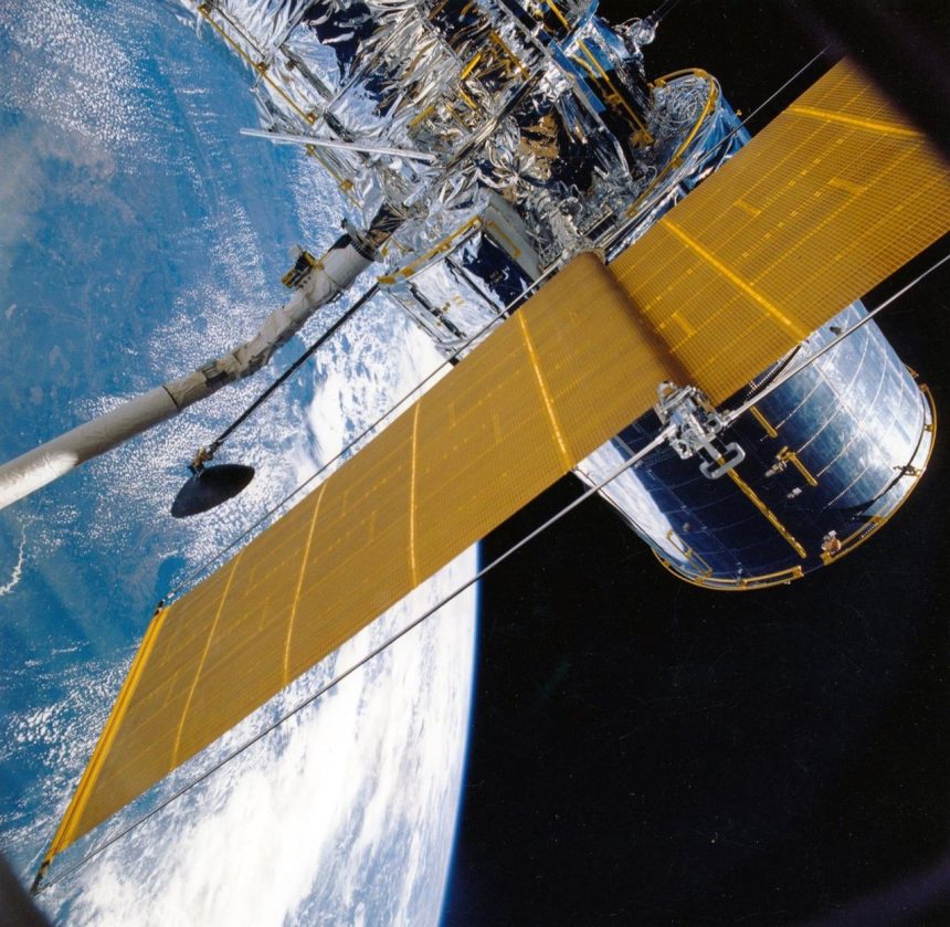 Espaçonave com painéis solares orbitando a Terra, vista contra o fundo escuro do espaço.