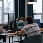 Equipe de desenvolvedores trabalhando em computadores em um escritório moderno de tecnologia.