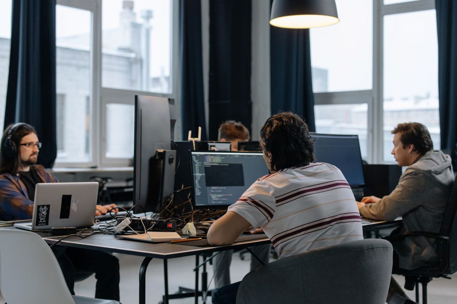 Equipe de desenvolvedores trabalhando em computadores em um escritório moderno de tecnologia.