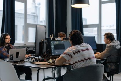 Equipe de desenvolvedores trabalhando em computadores em um escritório moderno de tecnologia.